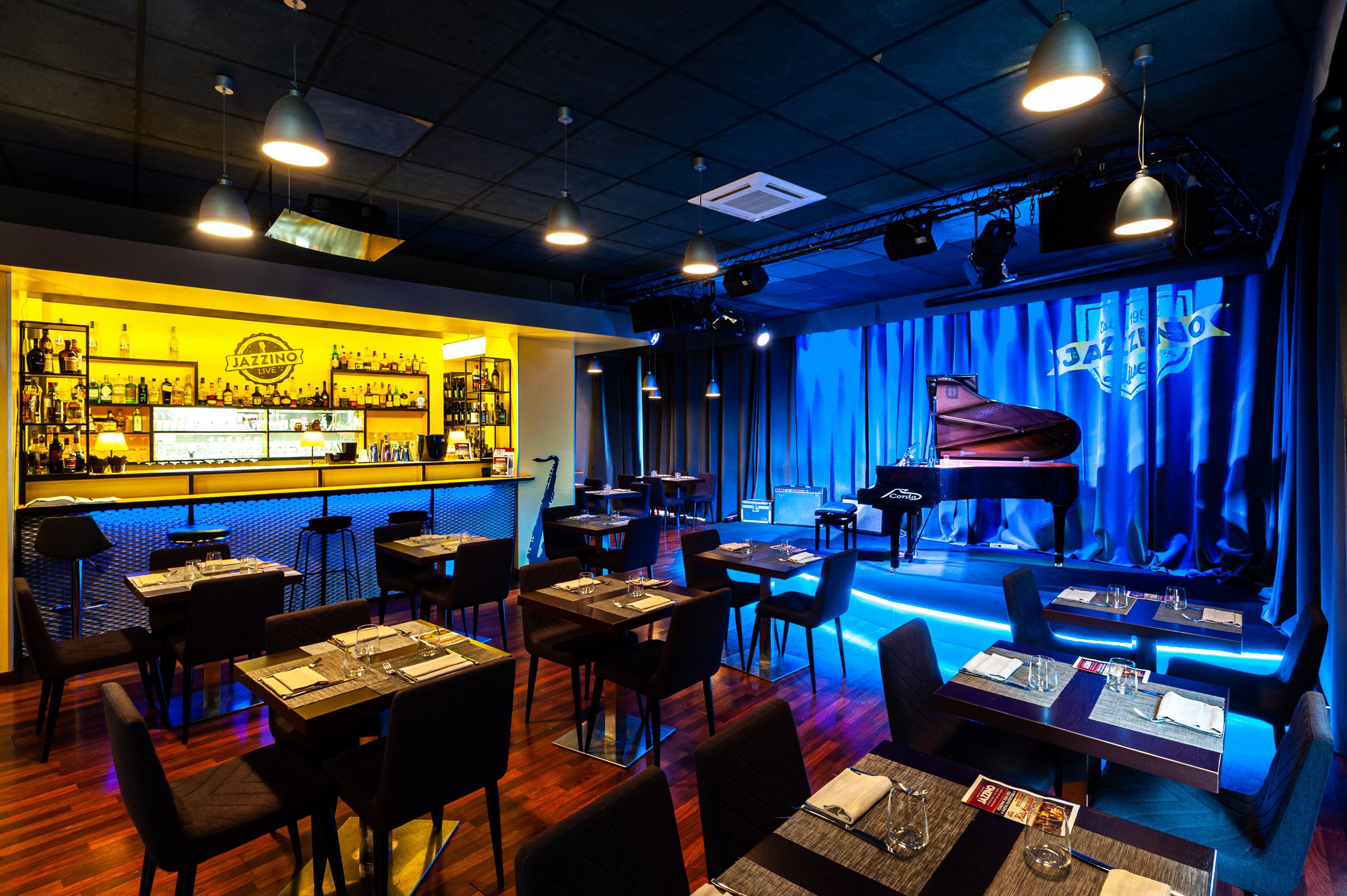 La sala del Jazzino con il pianoforte a coda sul palco e i tavoli del ristorante, a Cagliari